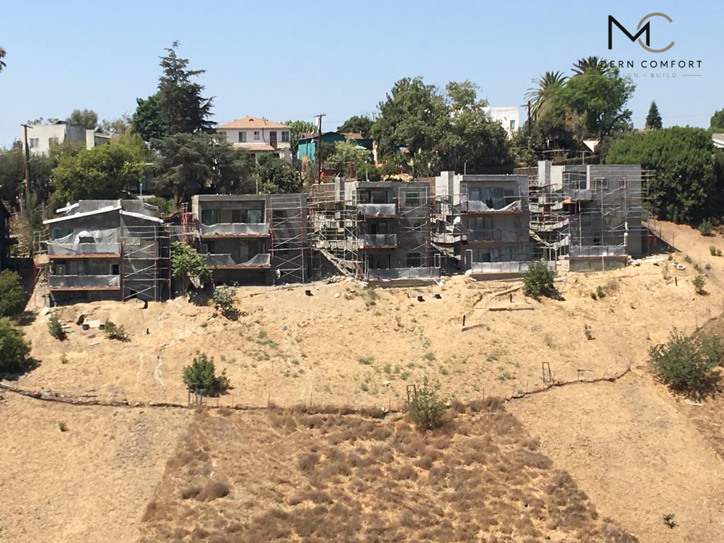 Hillside homes under construction with scaffolding on a graded slope