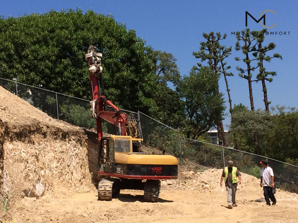 Drilling rig installing foundation caissons on a hillside construction site