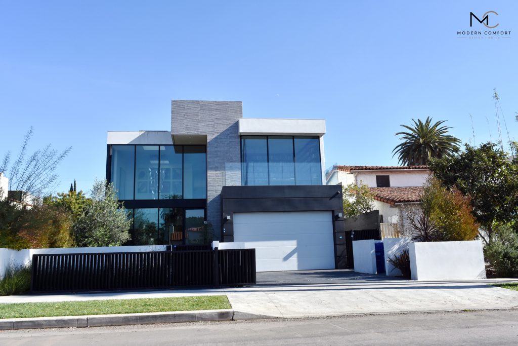 New construction modern home with floor-to-ceiling windows and black slat fence